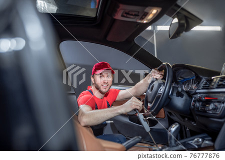 Auto mechanic troubleshooting car while working in cab Auto mechanic troubleshooting car while working in cab 76777876