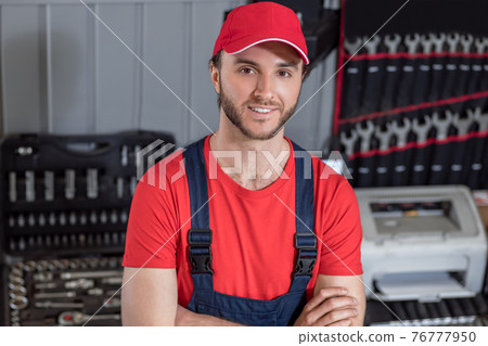Smiling man in workwear in repair shop Smiling man in workwear in repair shop 76777950