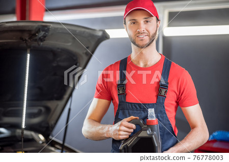 Man in overalls with canister in his hands 76778003