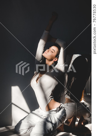 portrait of beautiful gentle woman in a white bodysuit posing in the sunshine. Black long hair. sensuality and tenderness portrait of beautiful gentle woman in a white bodysuit posing in the sunshine. Black long hair. sensuality and tenderness 76778530