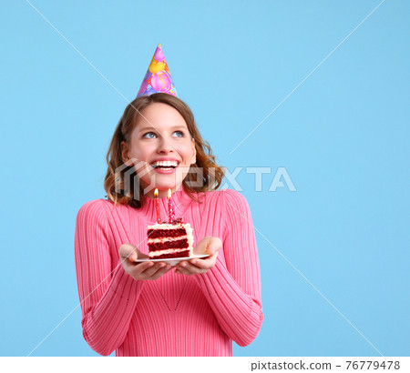 Delighted woman with cupcake making birthday wish Delighted woman with cupcake making birthday wish 76779478