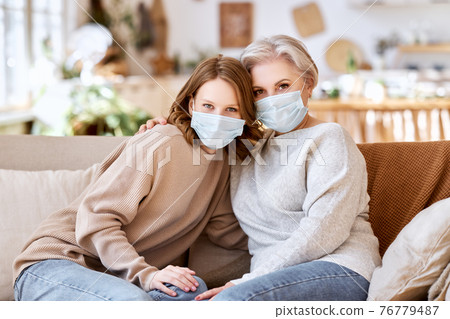 Unrecognizable young and senior women embracing and looking at camera on couch at home Unrecognizable young and senior women embracing and looking at camera on couch at home 76779487