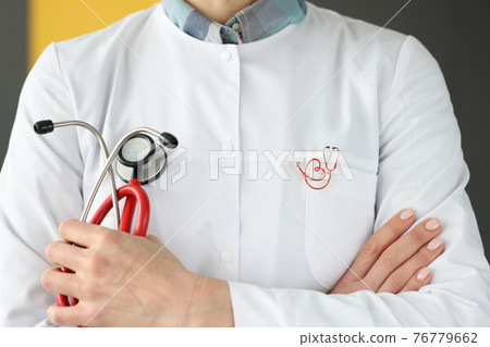 Doctor with brooch on uniform holding stethoscope closeup Doctor with brooch on uniform holding stethoscope closeup 76779662