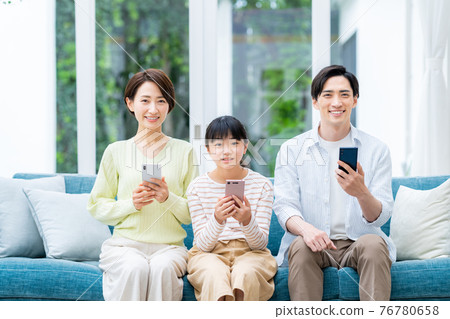 Middle family looking at a smartphone in the living room 76780658