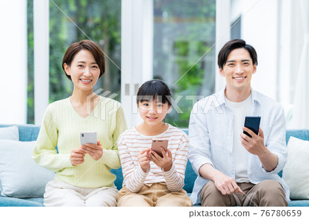 在客廳裡看智能手機的中產家庭 在客廳裡看智能手機的中產家庭 76780659