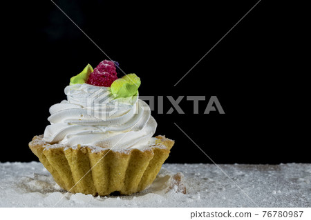 Cake with white cream decorated with berries on a wooden board on a black background. Cake with white cream decorated with berries on a wooden board on a black background. 76780987