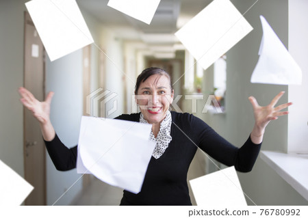 A woman in the office scatters papers. Nervous employee. 76780992