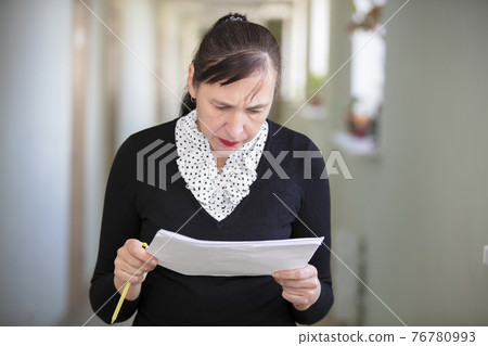 Woman at work. Female employee in the office corridor with paper. 76780993