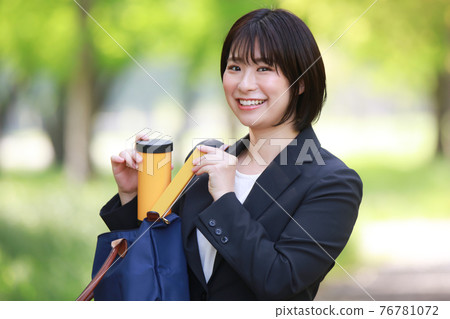 Female employee taking out a water bottle and chopsticks from a bag Female employee taking out a water bottle and chopsticks from a bag 76781072