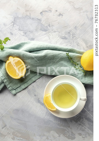 A cup of green tea with lemons and herbs, shot from above with copy space 76782313