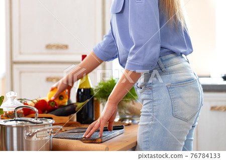 Unrecognizable woman standing in her kitchen close up Unrecognizable woman standing in her kitchen close up 76784133