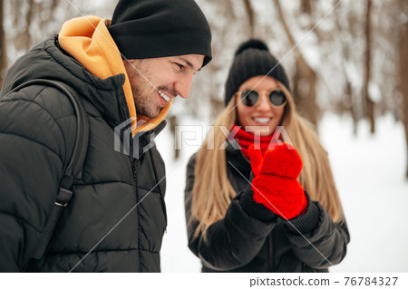 Happy couple hugging and smiling outdoors in snowy park 76784327