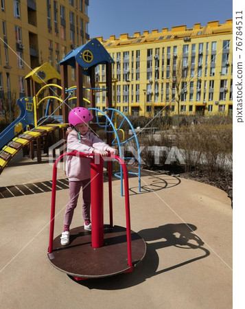 A girl of eight years in crash helmet riding on carousel. Child on merry-go-round 76784511