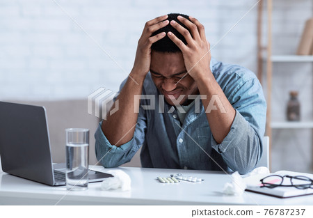 Black Man Suffering From Headache Touching Head Sitting At Workplace Black Man Suffering From Headache Touching Head Sitting At Workplace 76787237