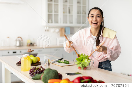 Portrait of smiling young woman cooking fresh salad Portrait of smiling young woman cooking fresh salad 76787564