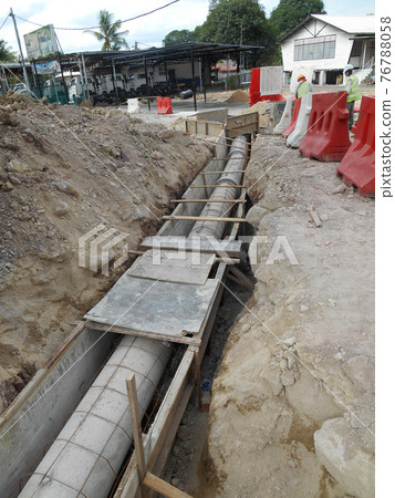 SEREMBAN, MALAYSIA -SEPTEMBER 28, 2016: Construction workers install underground precast concrete culvert at the construction site. SEREMBAN, MALAYSIA -SEPTEMBER 28, 2016: Construction workers install underground precast concrete culvert at the construction site. 76788058