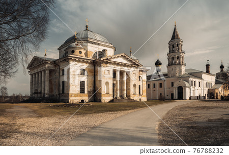 A church with a clock on the side of a road 76788232