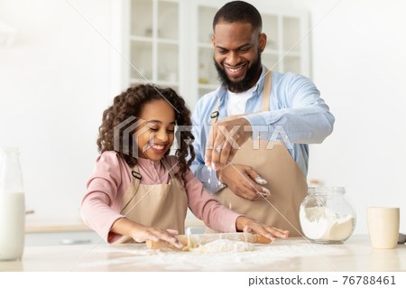 Happy black man and his child daughter kneading dough Happy black man and his child daughter kneading dough 76788461
