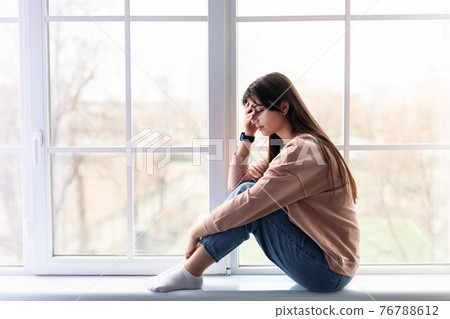 Sad woman crying near window at home 76788612