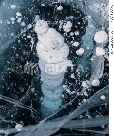 Frozen Baikal lake with cracks and methane bubbles on the transparent ice surface. Winter abstract and blue ice background. 76789356