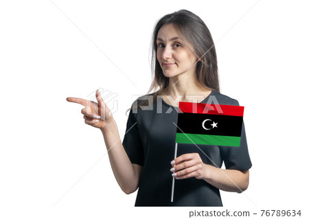 Happy young white woman holding flag Libya and points to the left isolated on a white background Happy young white woman holding flag Libya and points to the left isolated on a white background 76789634