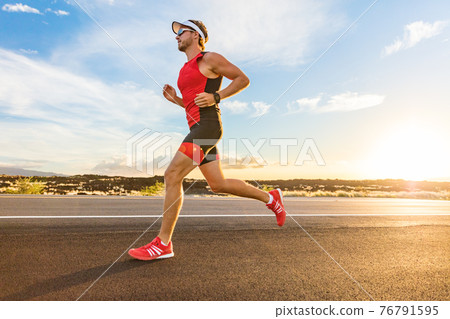 Triathlon - Triathlete man running in triathlon suit training for ironman race. Male runner exercising on Big Island Hawaii. Sunset 76791595