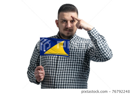 White guy holding a flag of Tokelau and a finger touches the temple on the head isolated on a white background White guy holding a flag of Tokelau and a finger touches the temple on the head isolated on a white background 76792248