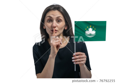 Happy young white woman holding flag of Macau and holds a finger to her lips isolated on a white background Happy young white woman holding flag of Macau and holds a finger to her lips isolated on a white background 76792255
