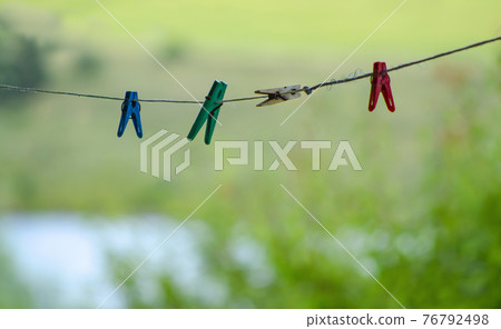 Colorful clothespin clothespins on the rope. Colourful cloth clips in a blue rope waiting for the next batch of clothes to come after laundry. 76792498