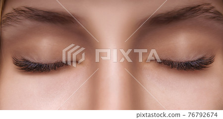 Eyelash Extension Procedure. Woman Eye with Long Eyelashes. Close up, selective focus. 76792674
