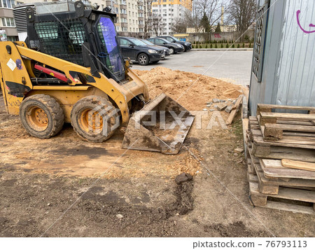 Mini excavator digging earth in a field or forest. Laying underground sewer pipes during the construction of a house. Digging trenches for a gas pipeline or oil pipeline. Earthwork, foundation pit 76793113