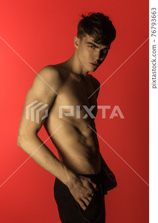 Muscle strong beautiful stripped male model in denim black jeans on red isolated font background Muscle strong beautiful stripped male model in denim black jeans on red isolated font background 76793663