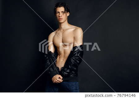 Male model in denim blue jeans and black leather jacket on black background 76794146