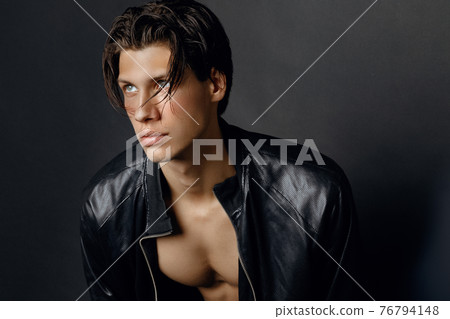 Male model in denim blue jeans and black leather jacket on black background Male model in denim blue jeans and black leather jacket on black background 76794148