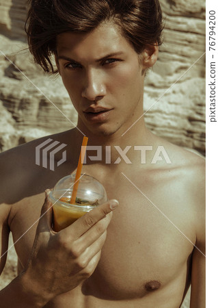 Sexy beauty male model lying stripped on the sand with nature background Sexy beauty male model lying stripped on the sand with nature background 76794200