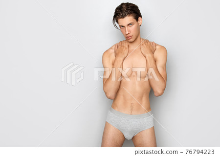 Guy in grey underwear on white background in studio isolated Guy in grey underwear on white background in studio isolated 76794223