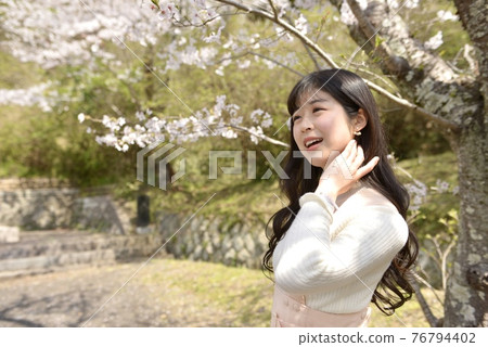 一個年輕苗條的女人在櫻花公園擺姿勢 76794402