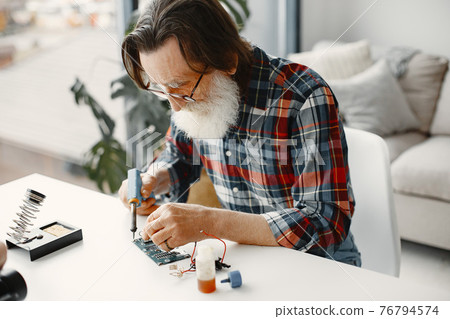 Male tech repairs electronic equipment at home 76794574