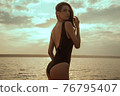 Stunning beautiful dark hair girl stripped in swimsuit on the sunset at he beach 76795407