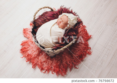 a baby in a basket sleeping and smiling a baby in a basket sleeping and smiling 76798672