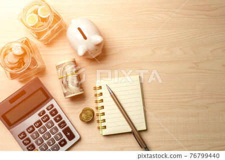 Piggy bank, calculator, dollar bill, glass jar filled with coins, notebook and pen, depict budget planning for basic needs, family,personal expense, Business and personal financial concept. Piggy bank, calculator, dollar bill, glass jar filled with coins, notebook and pen, depict budget planning for basic needs, family,personal expense, Business and personal financial concept. 76799440