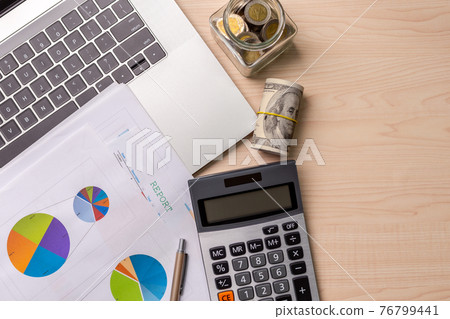 Calculator with a glass jar filled with coins, computer laptop, dollar bills, graph of investment with business stuff for saving money, with space for text. Business and personal financial concept. Calculator with a glass jar filled with coins, computer laptop, dollar bills, graph of investment with business stuff for saving money, with space for text. Business and personal financial concept. 76799441