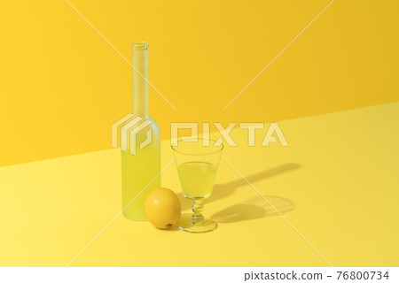 Lemon liqueur bottle and glass on a yellow background. Lemon liqueur bottle and glass on a yellow background. 76800734