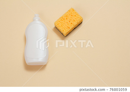 Bottle of dishwashing liquid and sponge on a beige background. 76801059