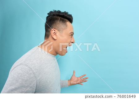 Closeup side view profile portrait of angry upset young man isolated on blue background. Closeup side view profile portrait of angry upset young man isolated on blue background. 76801649