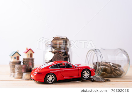 Jar full of coins with stack coin and red car on wooden table isolated grey background. Saving money and investment concept. 76802028
