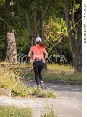 A woman running on a jogging course in the early summer evening A woman running on a jogging course in the early summer evening 76803052