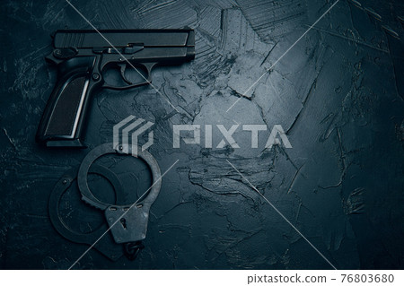 Gun and handcuffs on textured table. Gun and handcuffs on textured table. 76803680