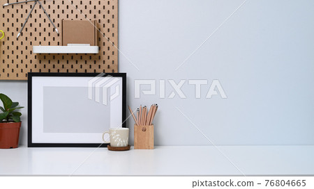 Home office desk with empty photo frame, coffee cup, house plant and pencil holder. Home office desk with empty photo frame, coffee cup, house plant and pencil holder. 76804665