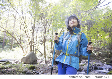 Trekking image of a young woman walking on a mountain road 76804875